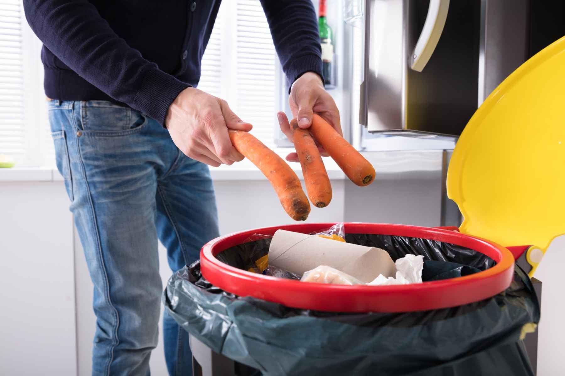 Persona tirando zanahorias a la basura
